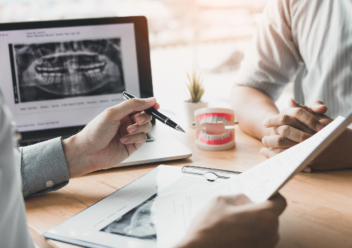 Dental patients weighing the pros and cons of implants with his dentist.