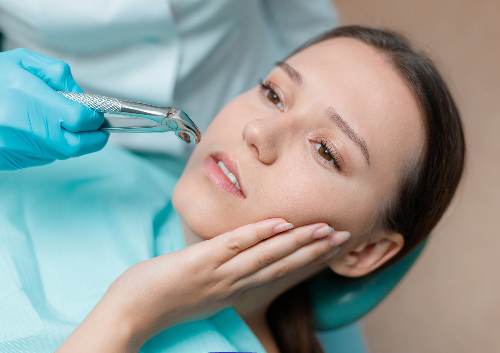 Woman in dental chair holding her cheek due to wisdom tooth pain.