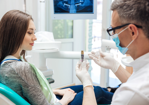 Dentist showing his female patient a dental implant